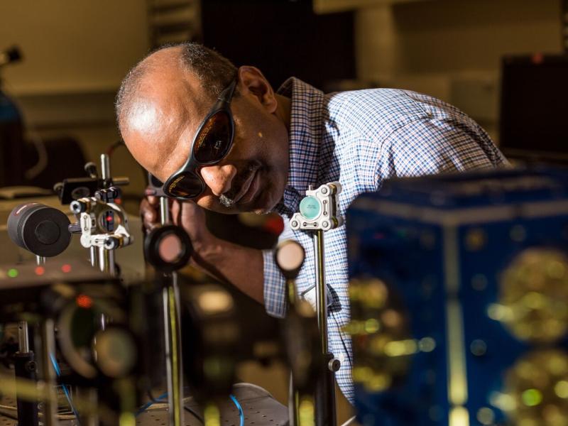 Sivanandan Harilal, wearing safety eyewear, leaning over a machine.